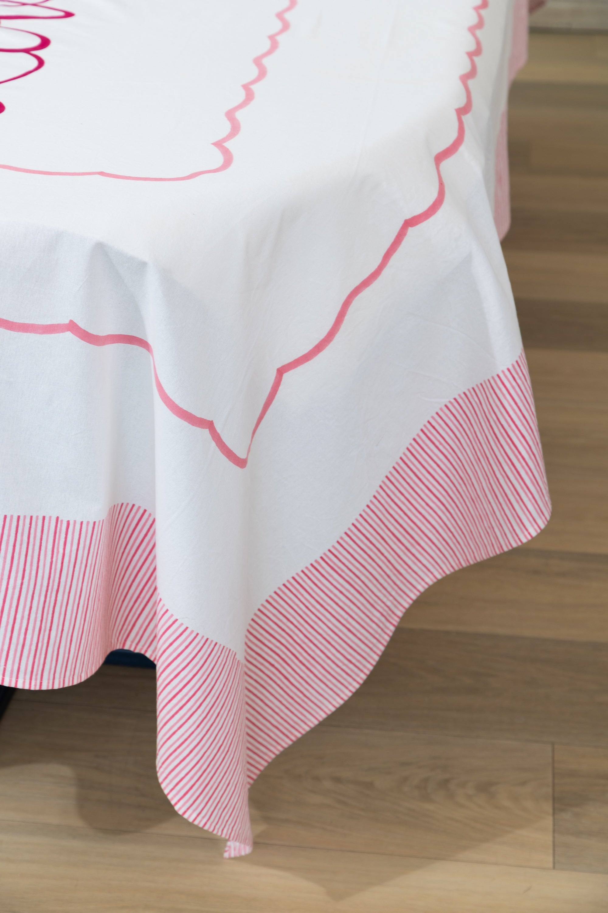 White tablecloth with pink decorative trim on a wooden floor