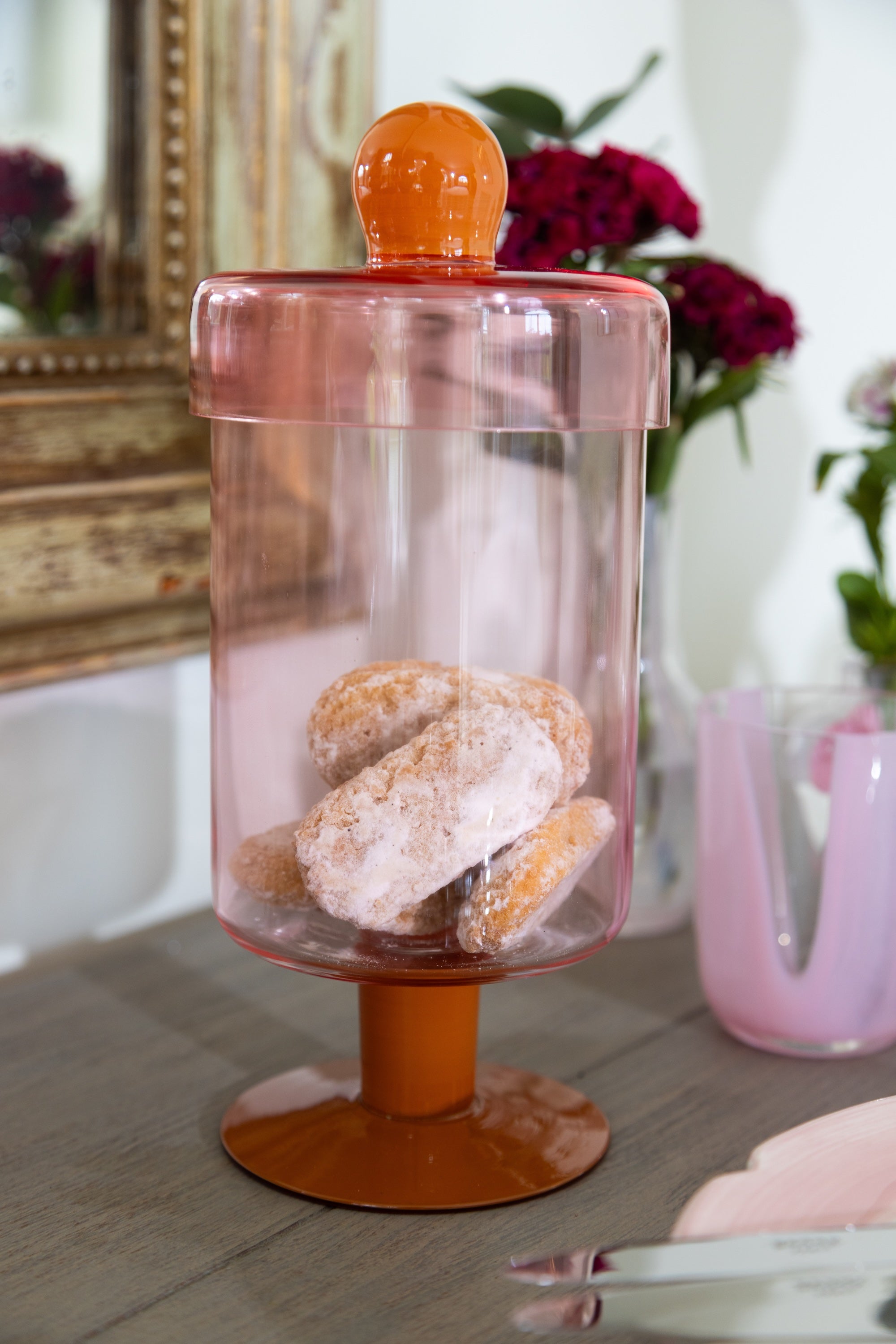 Clear container with orange base and lid on a table, filled with pastries.